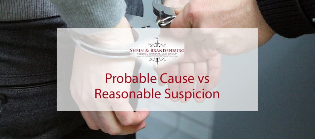 Featured Image for a blog about probable cause vs reasonable suspicion. Image shows a mans hands being handcuffed by a police officer.